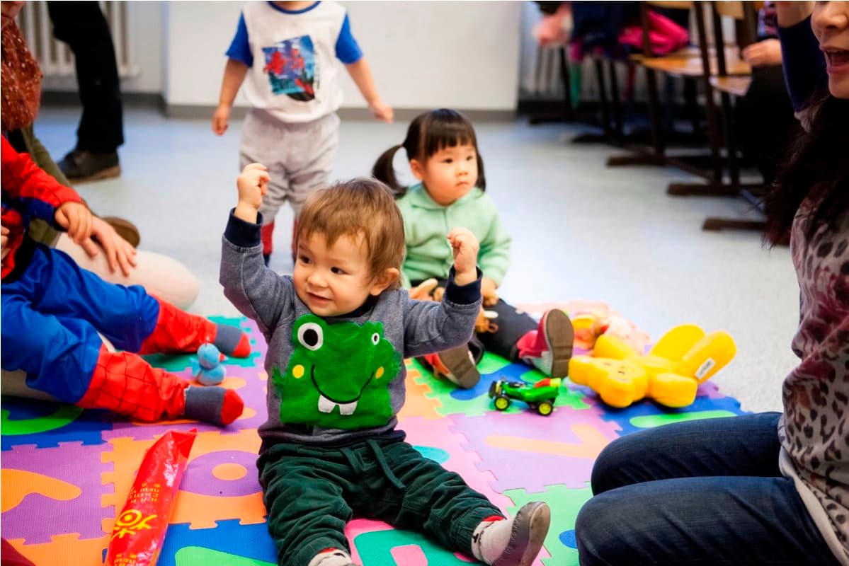 Kleinkind spielt auf einer bunten Spielmatte im Eltern-Kind-Kurs.